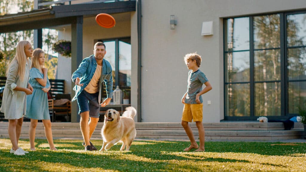Les membres d'une famille devant leur maison aux grandes fenêtres PVC