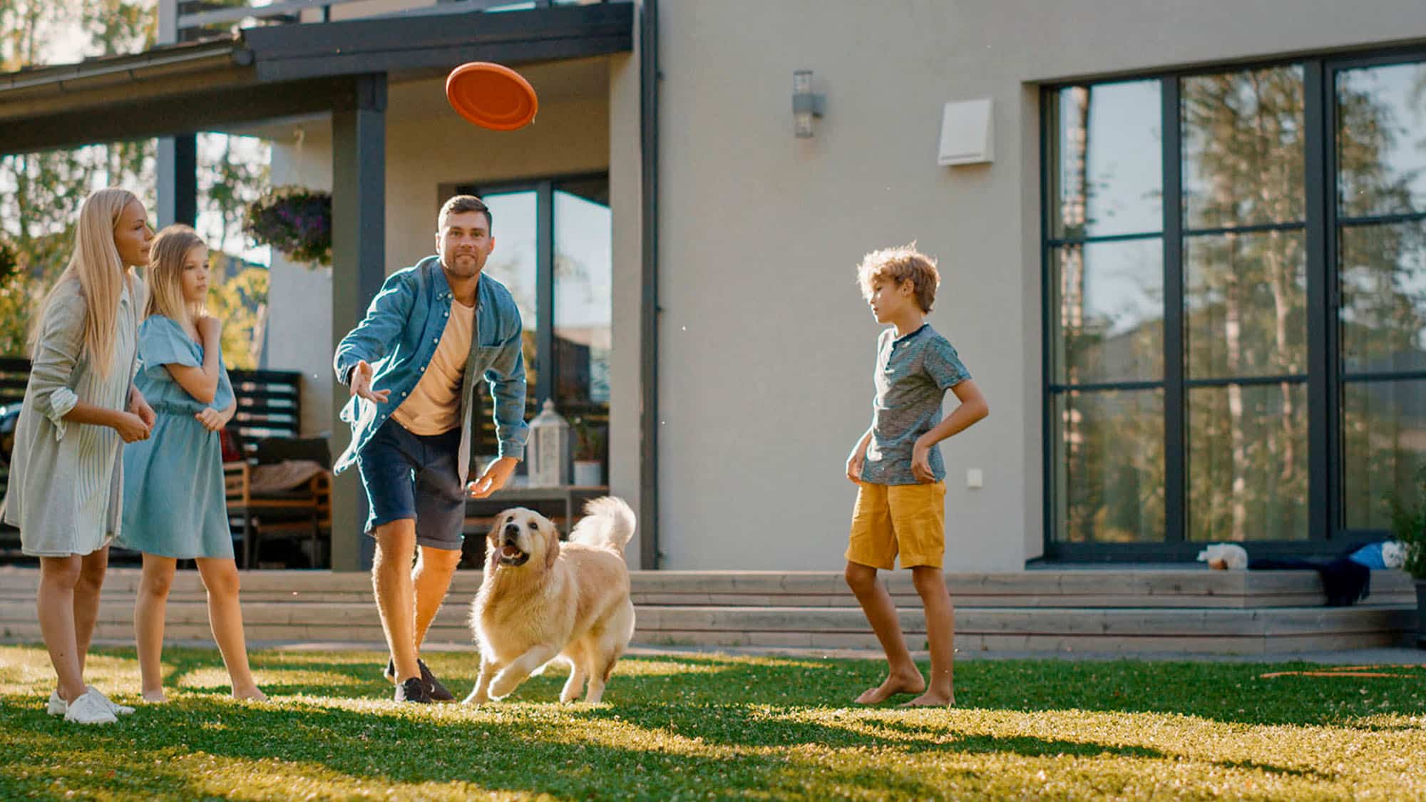 Les membres d'une famille devant leur maison aux grandes fenêtres PVC